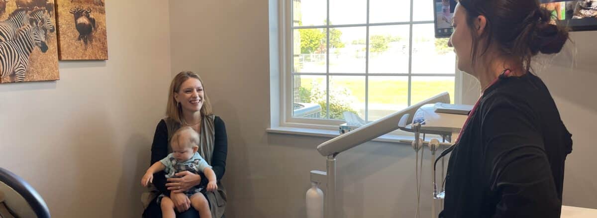 A mother and her son talking with the dental hygienist at his first pediatric dental appointment