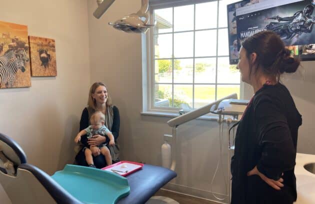 A mother and her son talking with the dental hygienist at his first pediatric dental appointment