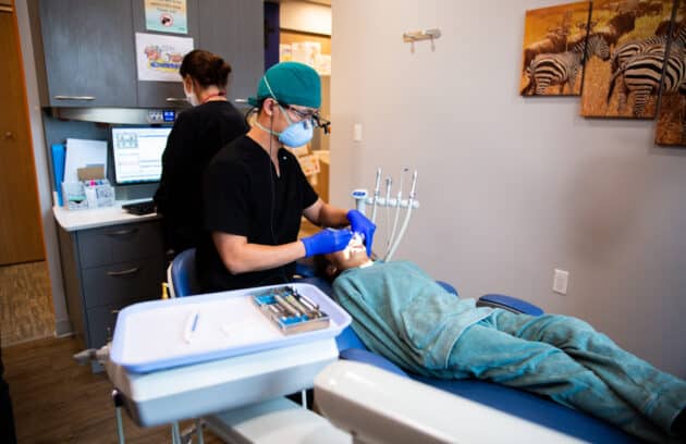 A pediatric dentist examining a young patient during a routine dental exam