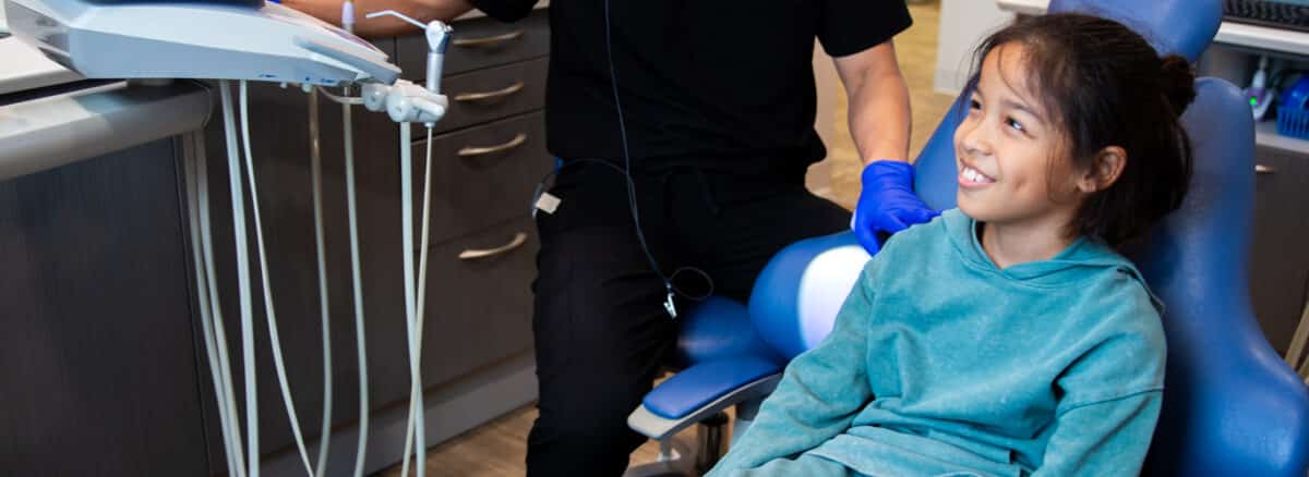 Young dental patient smiling while talking with his pediatric dentist