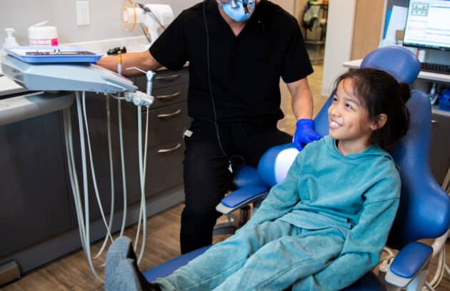 Young dental patient smiling while talking with his pediatric dentist