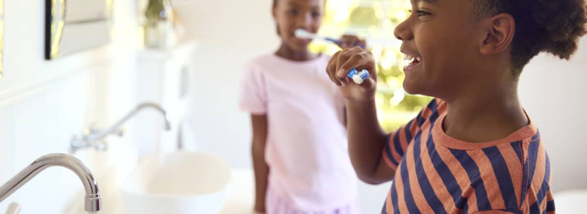 Brother And Sister In Bathroom At Home Brushing Teeth Together