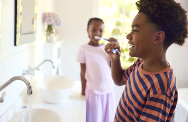 Brother And Sister In Bathroom At Home Brushing Teeth Together