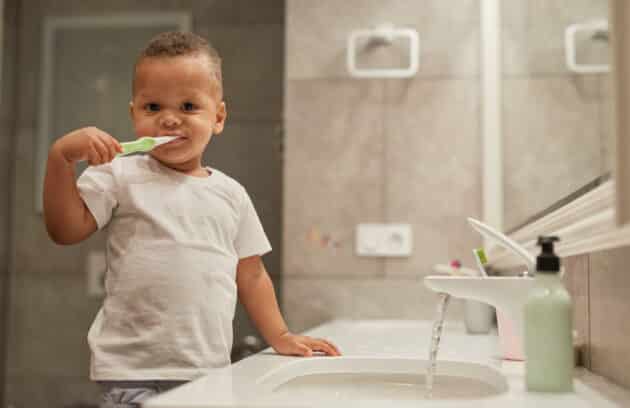 Photo of a cute toddler boy brushing teeth in the bathroom